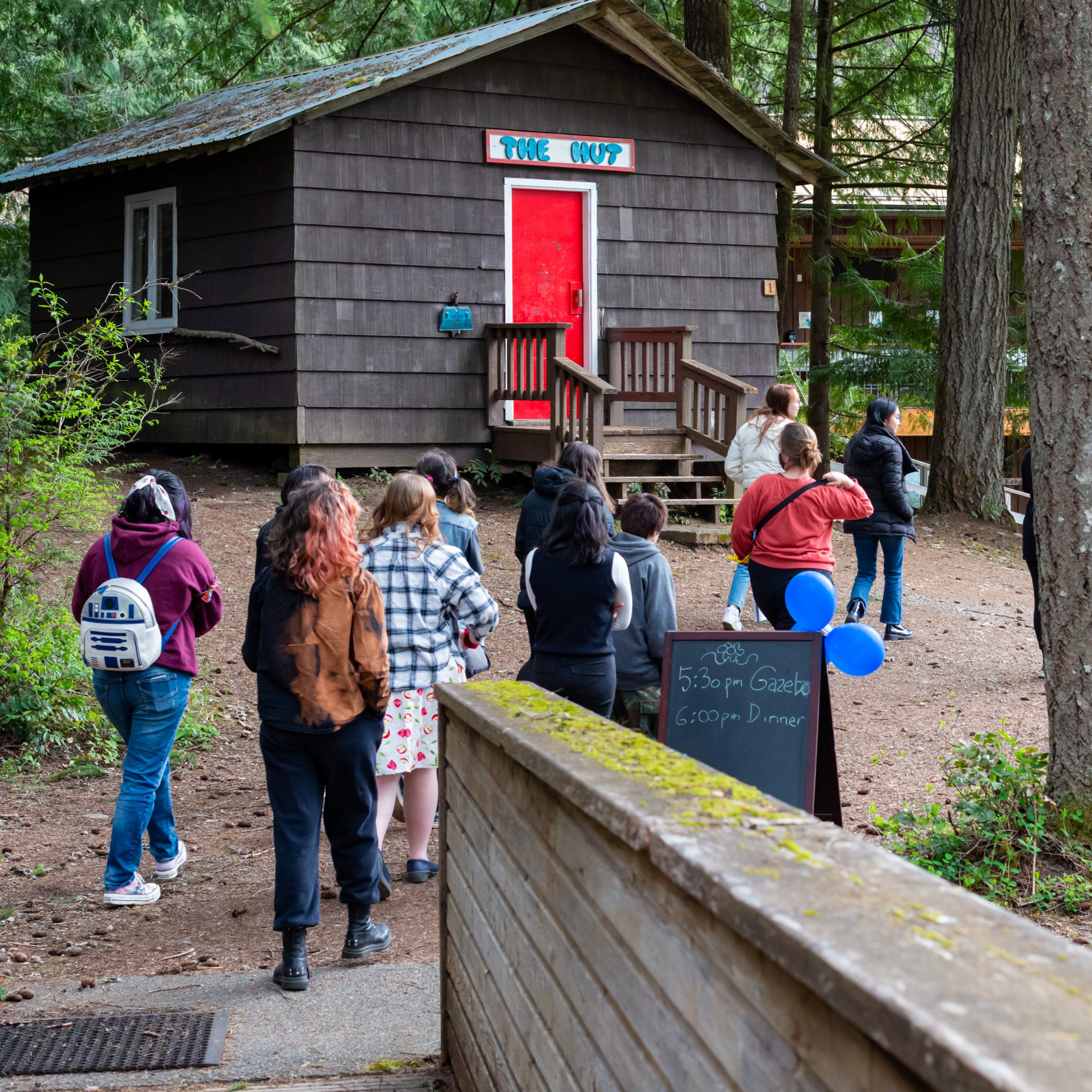 A group of young people are walking outside of a camping cabin.